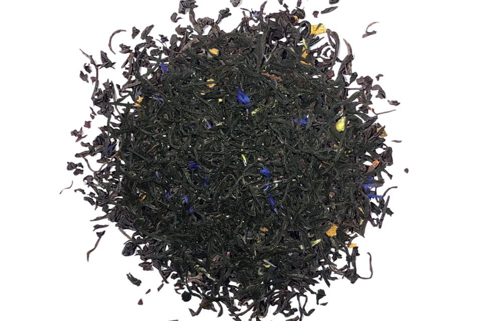 A close-up of loose black tea leaves with small pieces of blue blossoms, bergamot, and citrus pieces.