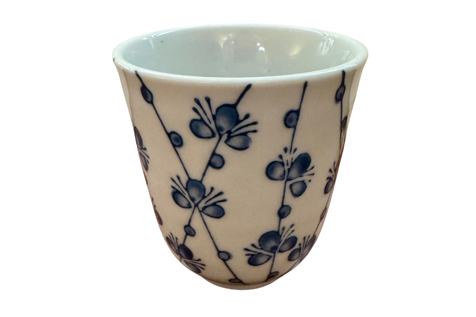 White ceramic cup with blue floral patterns on a white background