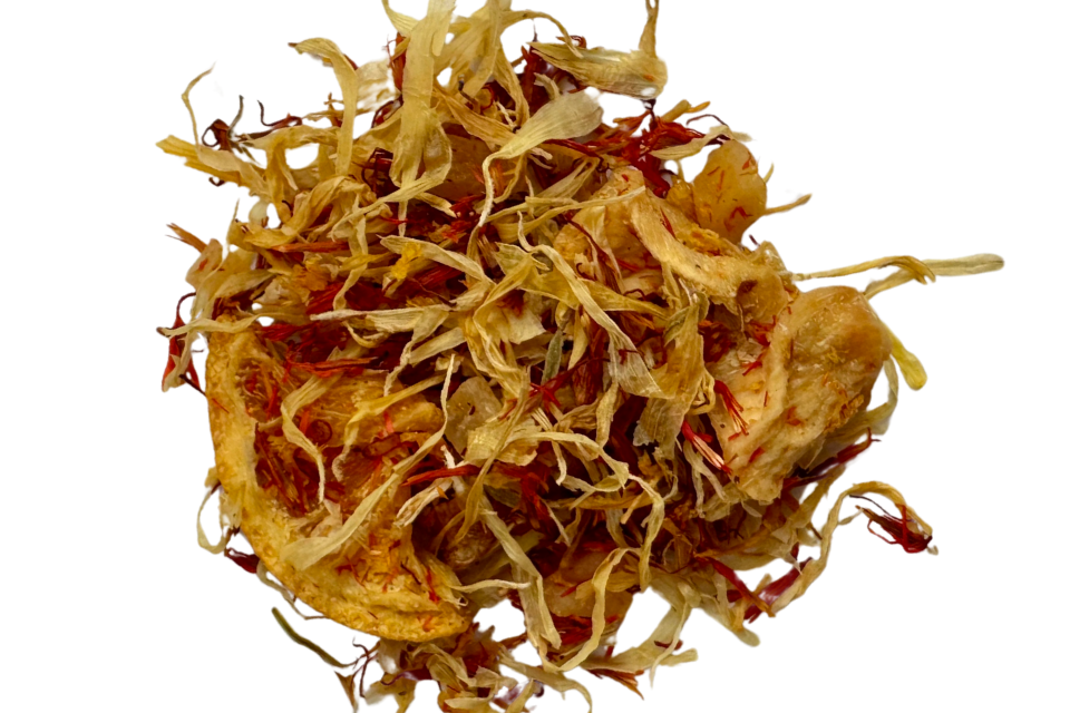 A cup of Golden Oasis Tisane Tea with a variety of dried fruit pieces and floral petals.