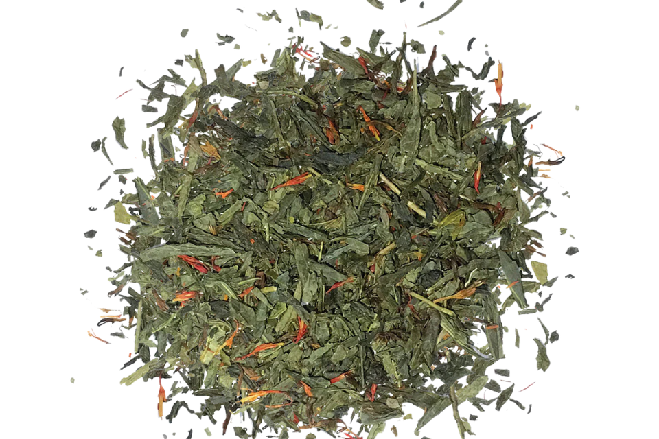A close up image of dried green tea leaves with hints of red, indicating the presence of pomegranate flavor.