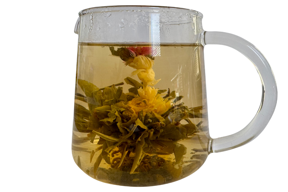 Clear glass mug with floral tea leaves and yellow flowers on a white background