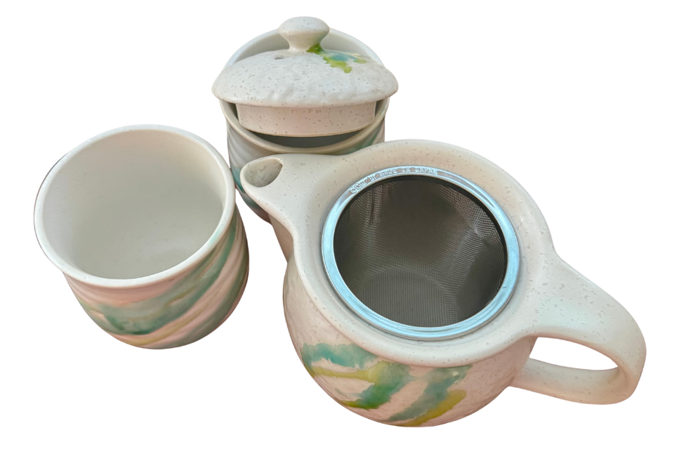 Ceramic teapot and cup set with floral design on a white background