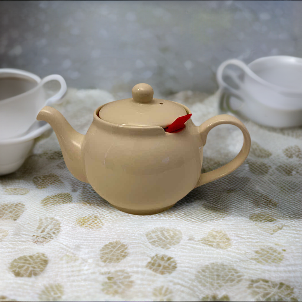 A cream colored chatsford teapot on a table with white teacups.