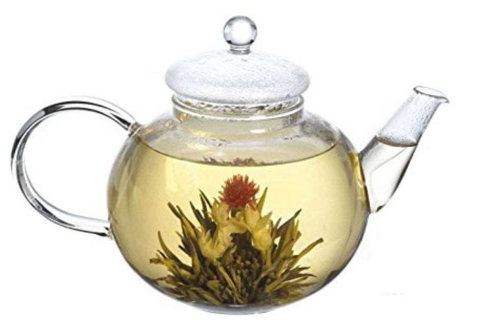 Clear glass teapot with a floral tea ball inside on a white background