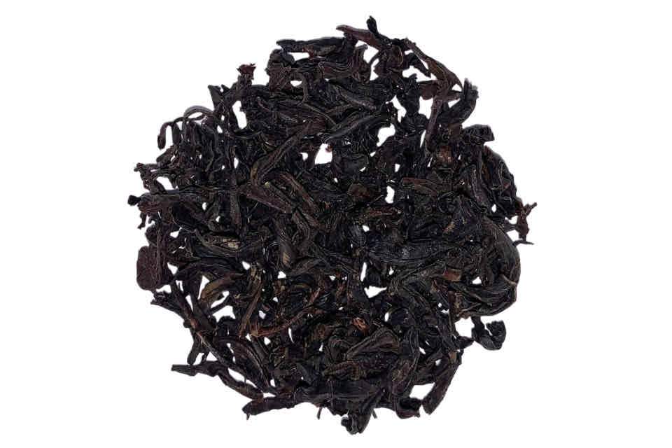 a close up of keemun black tea leaves on a white background