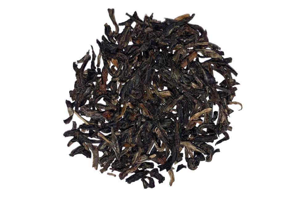 A close-up image of dried black tea leaves showing various shades of brown and some fine tips.