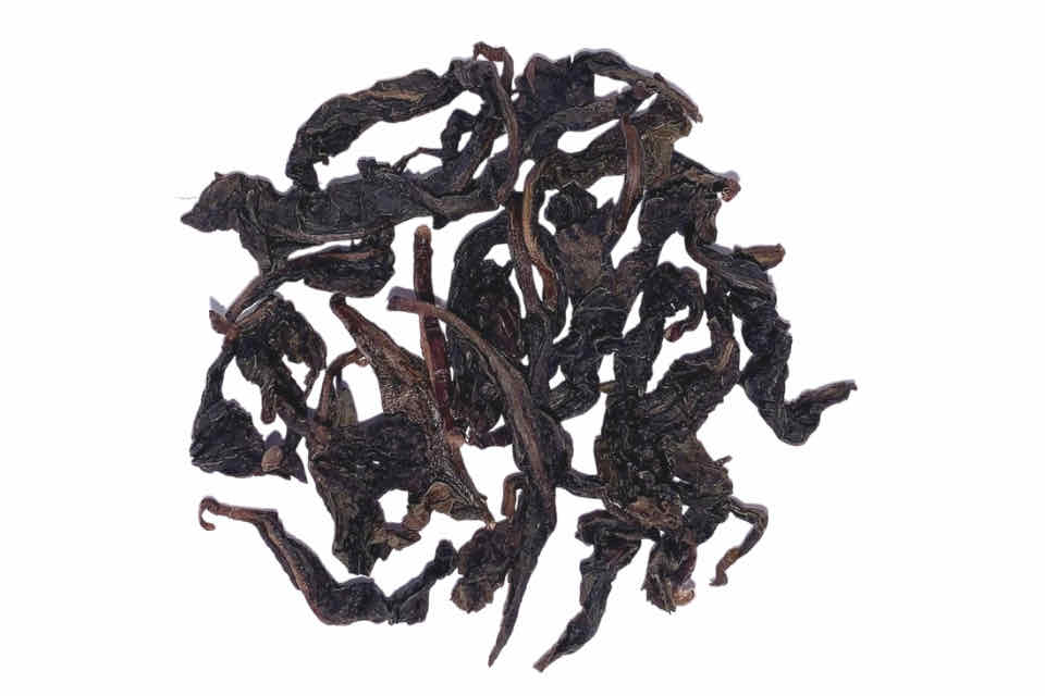A heap of dark, oxidized oolong tea leaves on a white background.