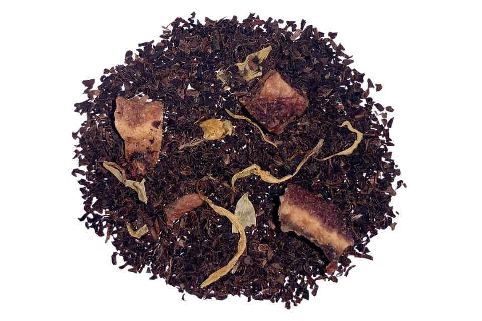 A close-up image of Decaf Peach Black Tea leaves, showing a mix of black tea particles and peach pieces, with a hint of marigold flowers.