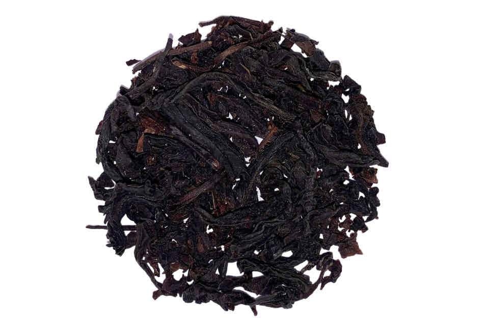 A pile of loose black tea leaves, with oil of bergamot and a mix of brown and black leaves, resembling a round shape.