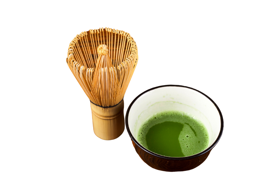 a matcha whisk and a china cup with matcha liquid on a white background