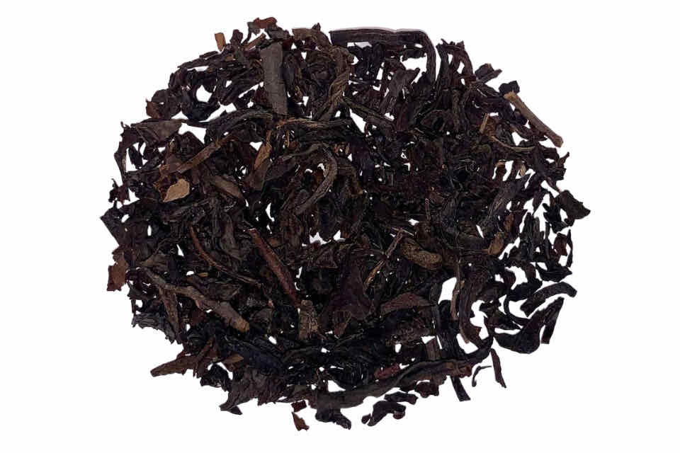 A close up image of dry black tea leaves with hints of reddish-brown, indicative of the smoky aspect of the tea blend.