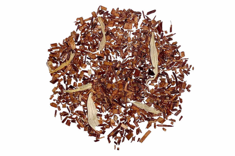 A pile of dried rooibos tea leaves with a peach coloration, indicating a natural peach flavor.