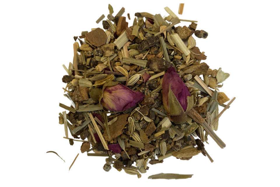 A heaping spoonful of Shanti Ayurvedic Tea, showcasing a variety of dried herbs and spices including tulsi, saffron, fennel, and rosebuds.