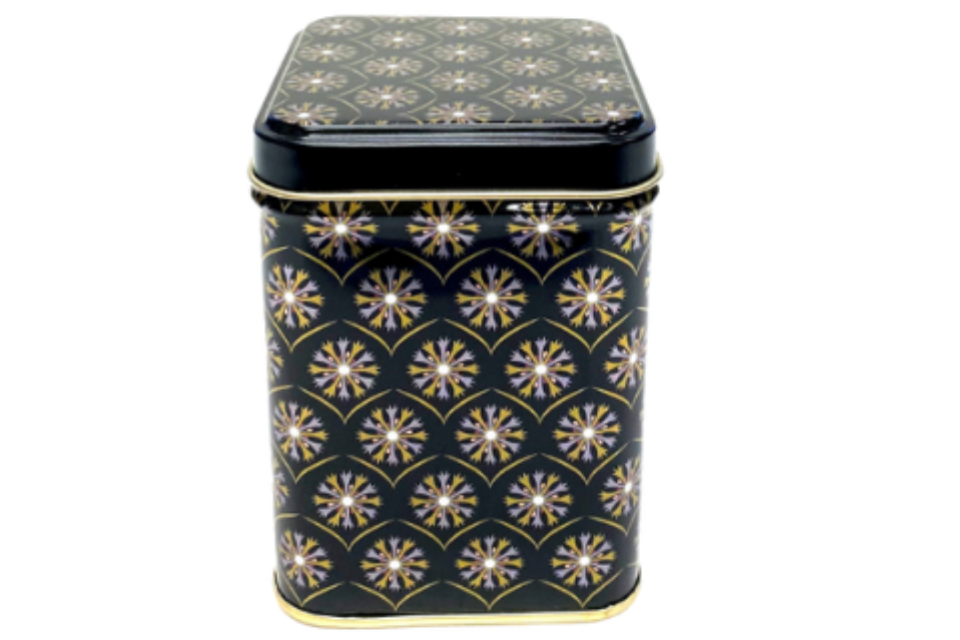 A black and gold tea storage canister with a starburst pattern.