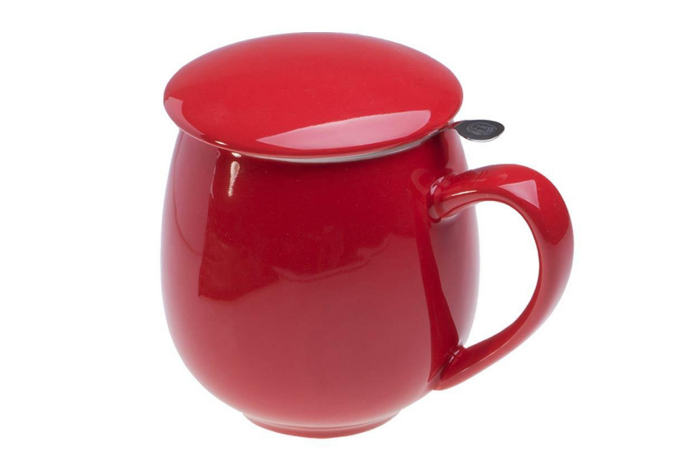 A red porcelain teacup with an infuser basket and matching lid.