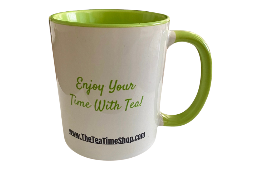 A white mug with a green handle and green interior. Hand-painted enjoy your time with tea on the cup.