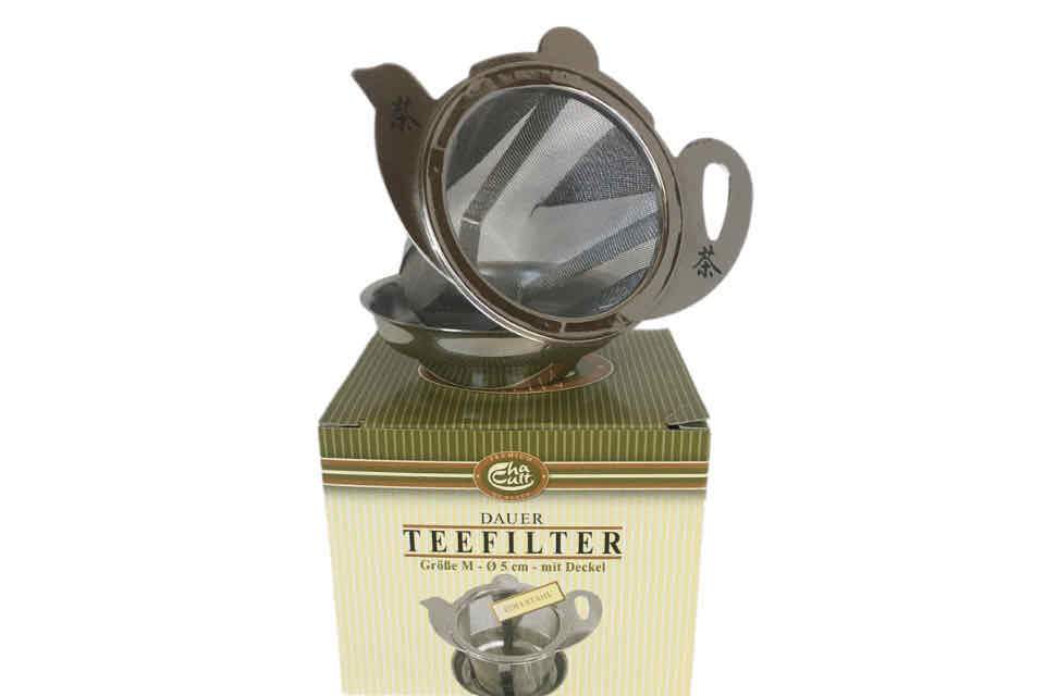 A stainless steel Teapot Brew Basket with a fine mesh, placed on top of a tea box with the product name visible.