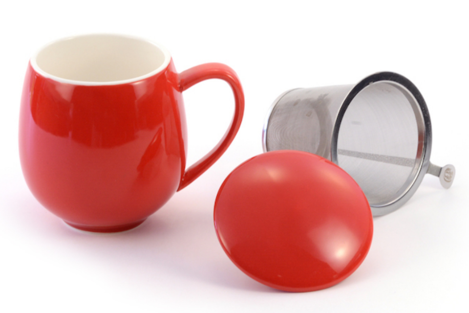 A red teacup with a matching lid and an infuser basket.