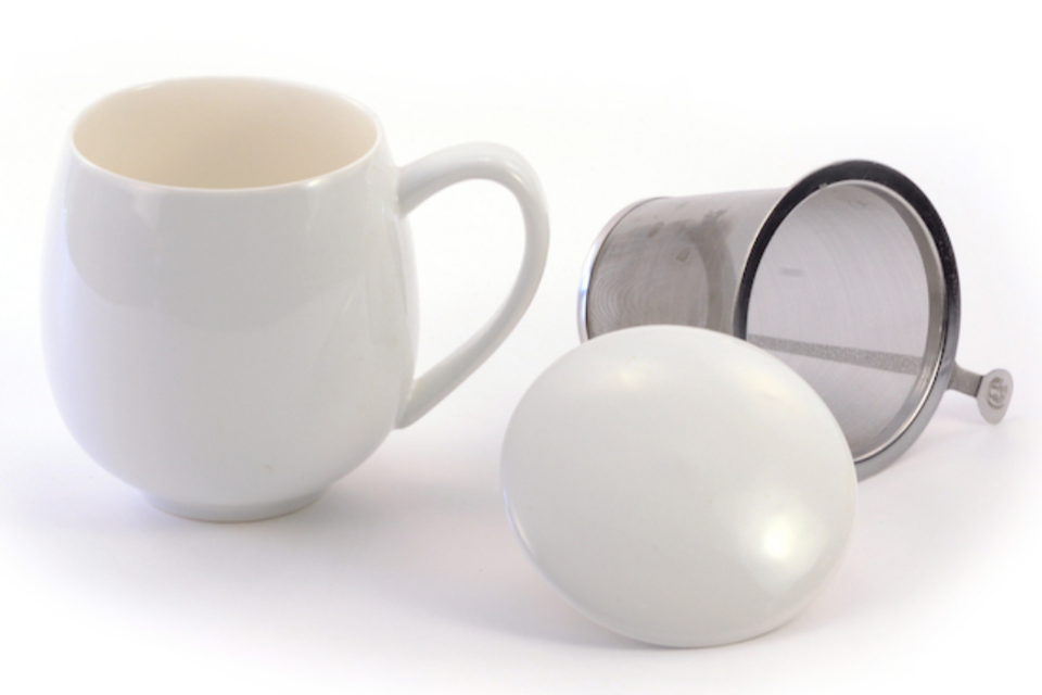 A white teacup with an infuser basket and a matching lid.