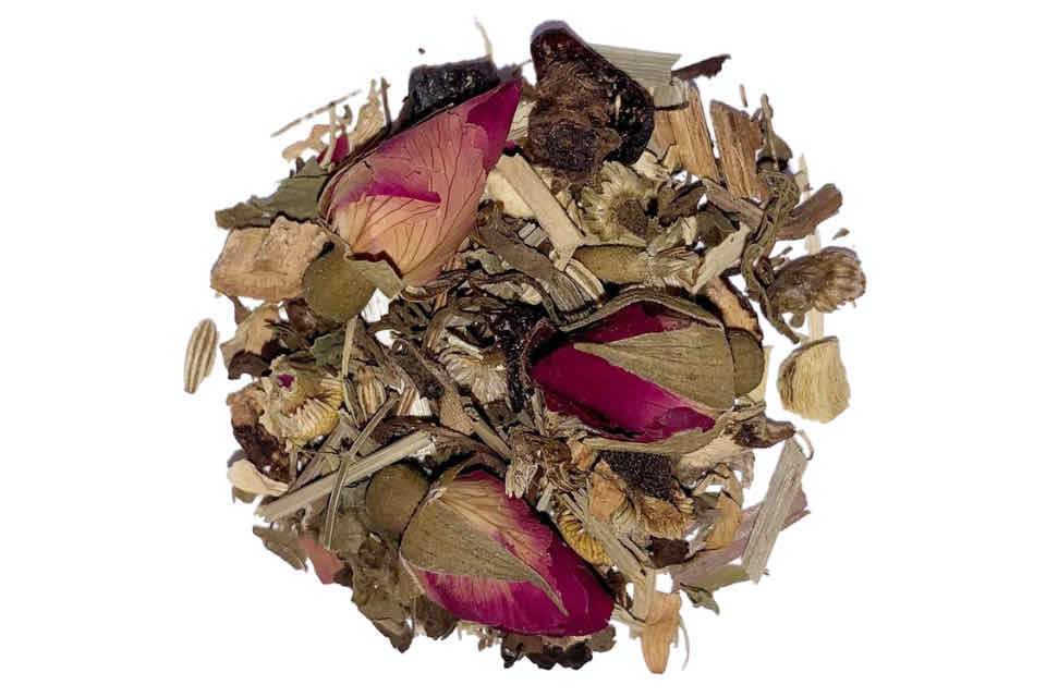 A heap of dried herbal tea ingredients including chamomile, saffron, licorice, ginger root, fennel seeds, rosebuds, spearmint, rose hips, lemongrass, tulsi, and natural orange flavor.