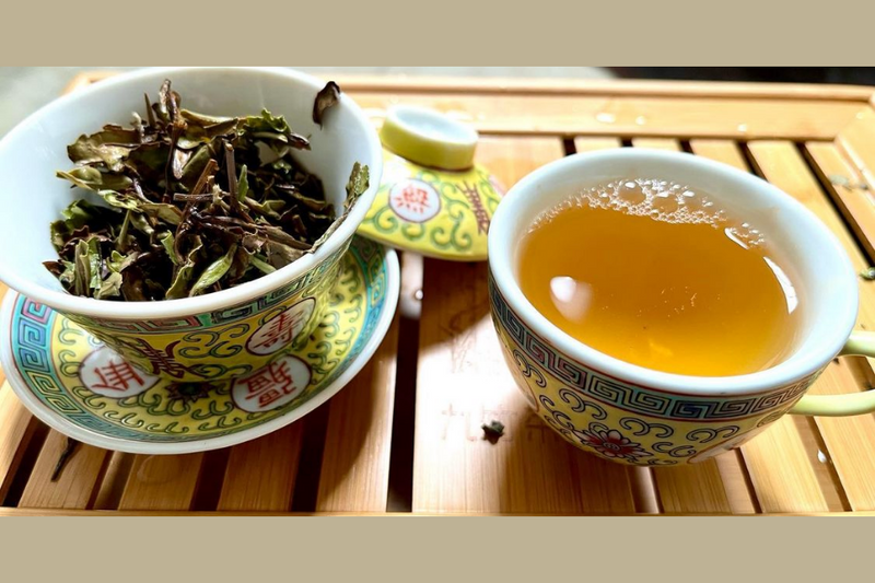 white peony tea leaves and steeped tea in a cup